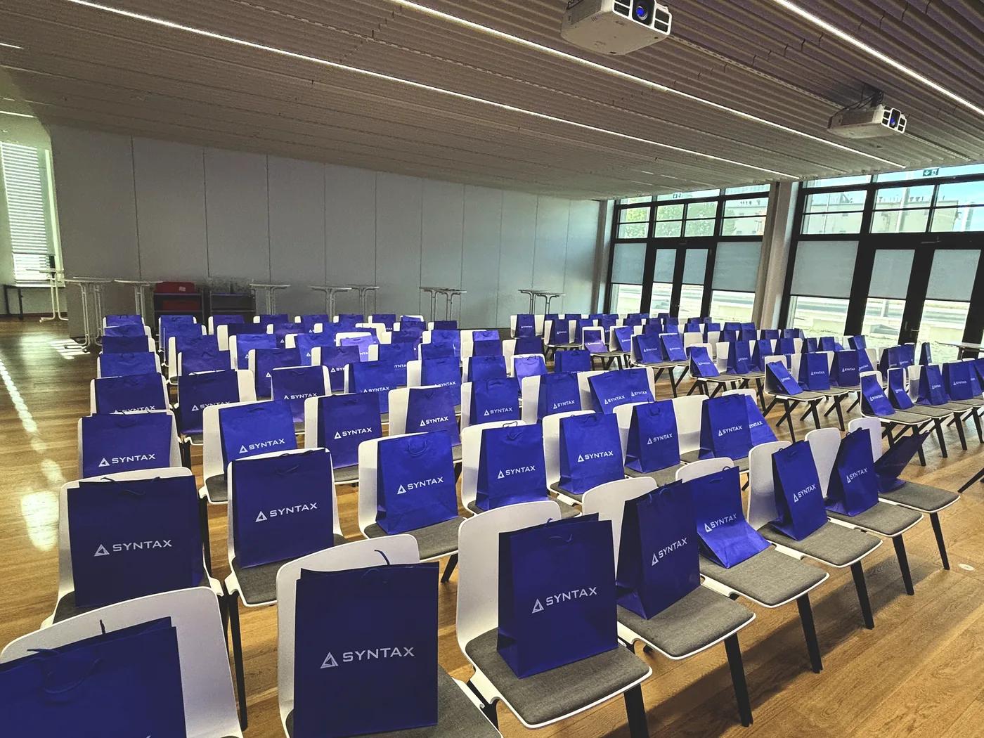 Rows of chairs with a Syntax tote bag on every seat, shortly before the doors opened