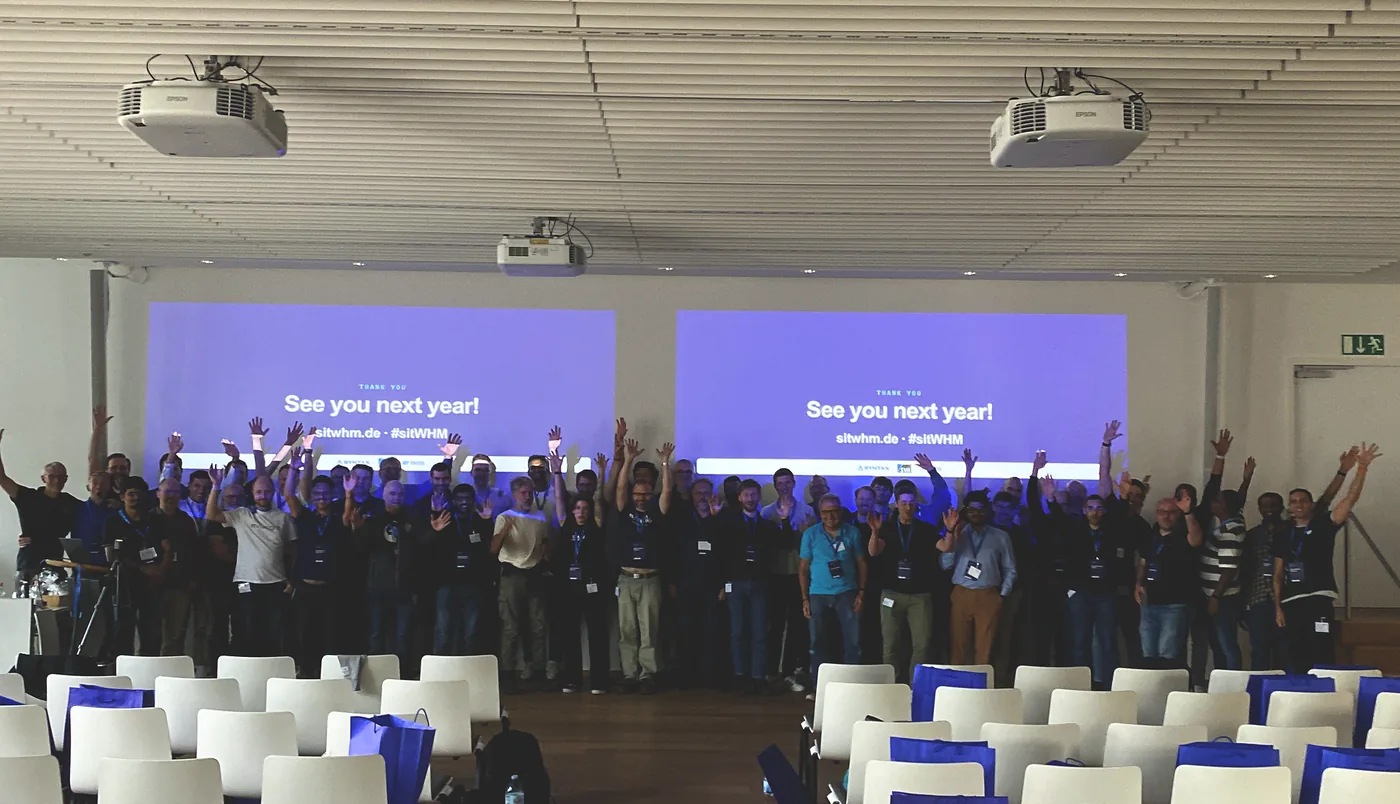 Everyone gathered for the closing group photo, hands in the air, 'See you next year!' on the screens