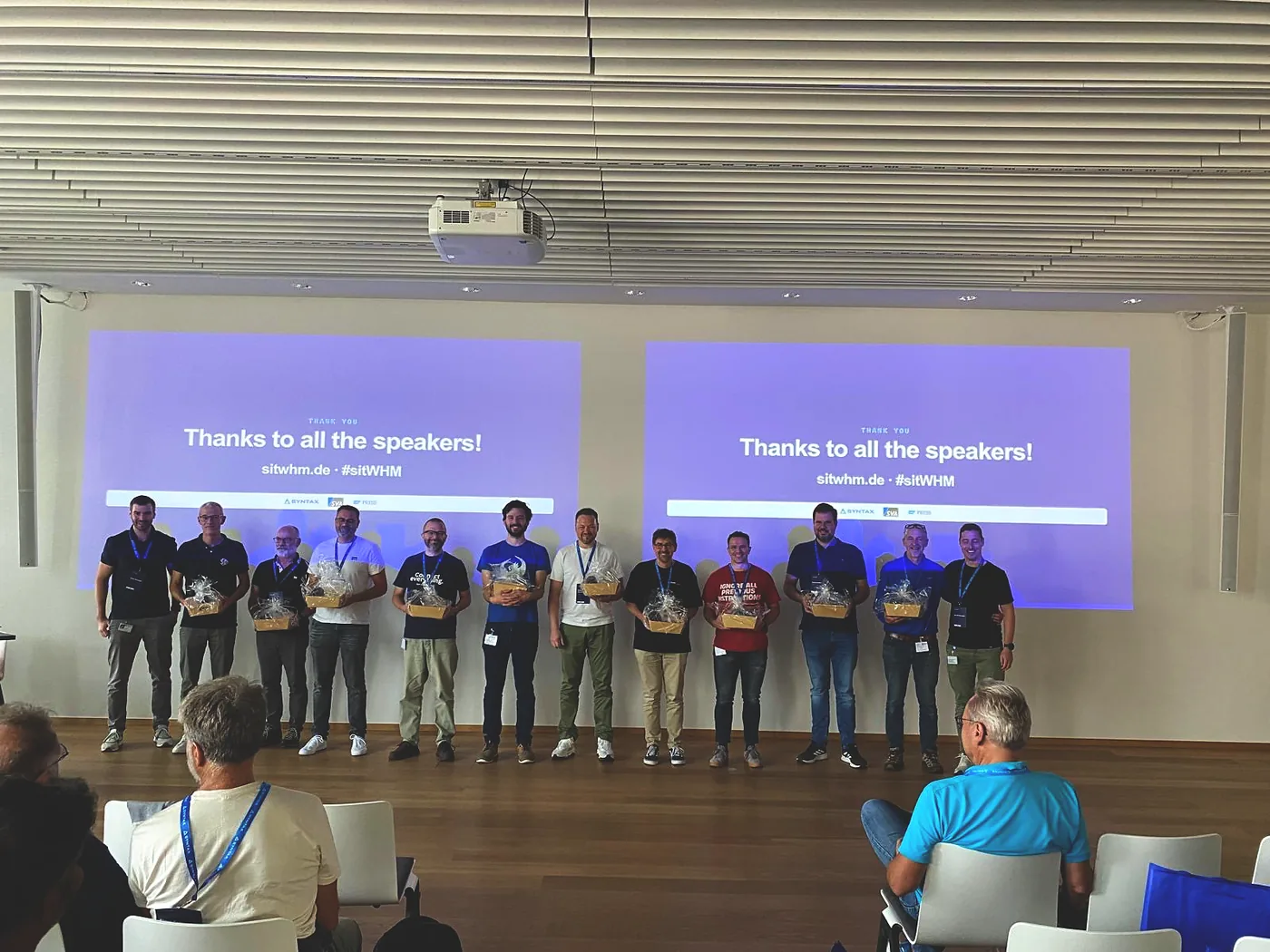 The speakers lined up on stage with their gifts, 'Thanks to all the speakers!' on the screens